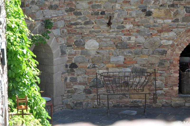 Castello Di Amorosa: каменная стена с арками и металлической корзиной